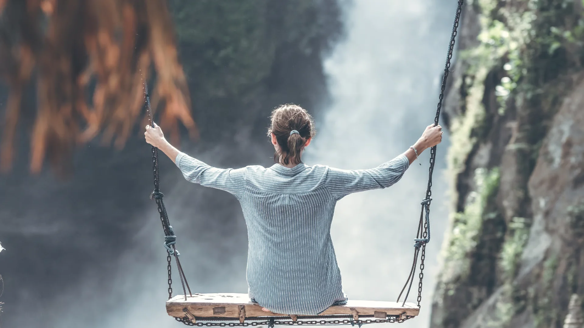 Woman on a swing overlooking a waterfall